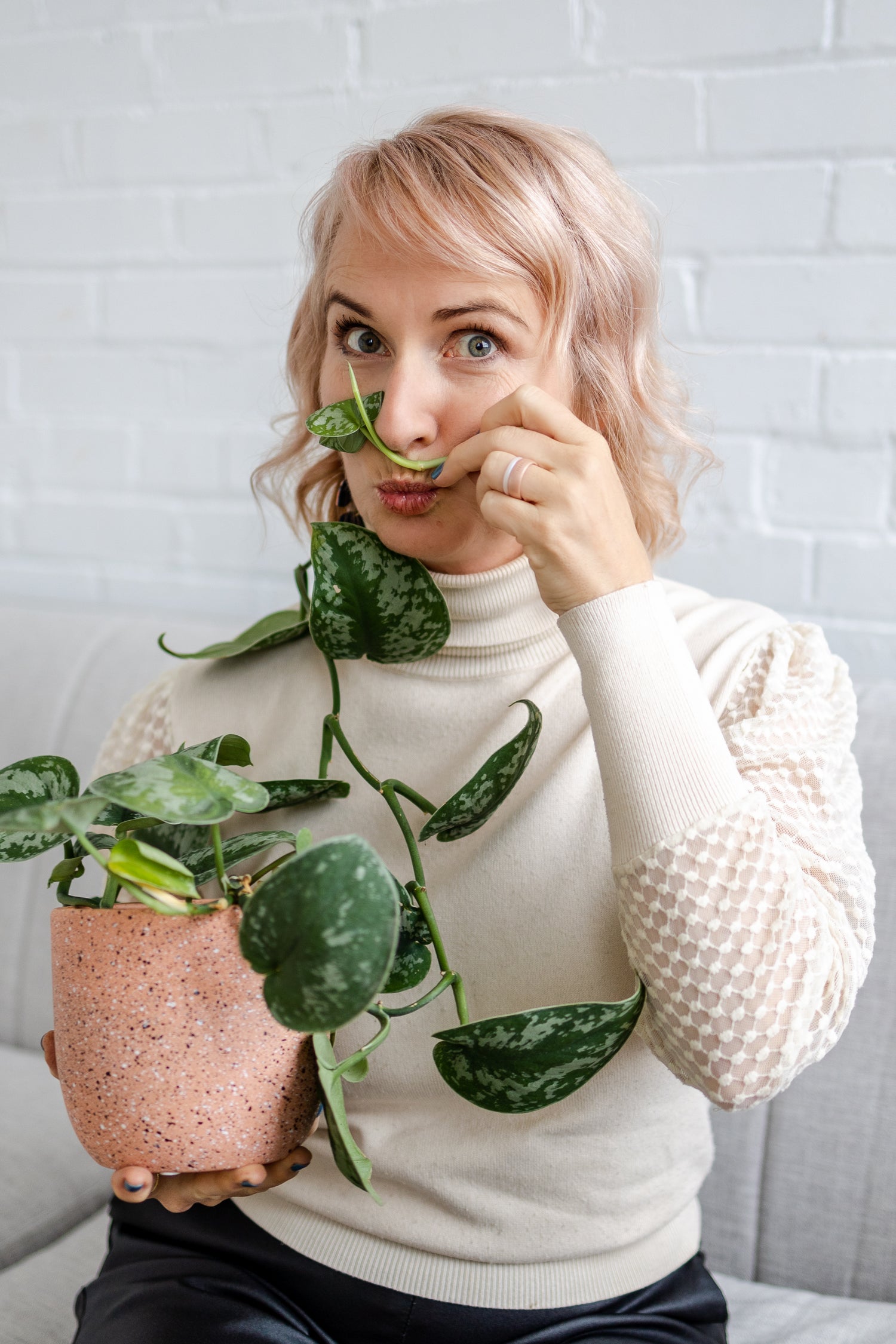 A photo of Sarah Peel, founder of Happy Kitty Salve making a funny face against a white brick background